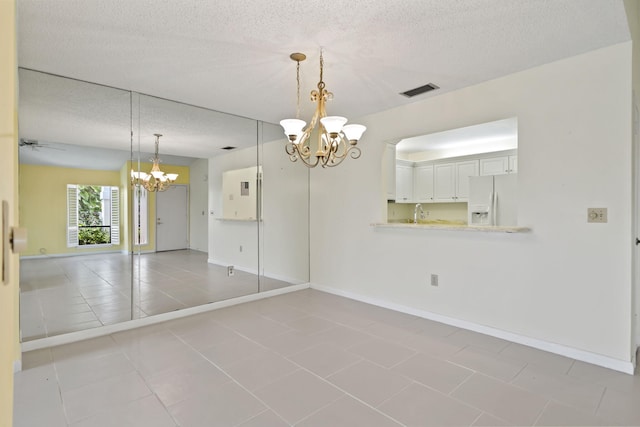 5623 SE Foxcross Pl, Stuart, FL 34997 - spare room featuring a chandelier, a textured ceiling, and light tile patterned flooring