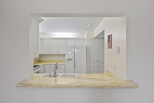 5623 SE Foxcross Pl, Stuart, FL 34997 - kitchen featuring white fridge with ice dispenser, range, white cabinetry, light countertops, and a peninsula