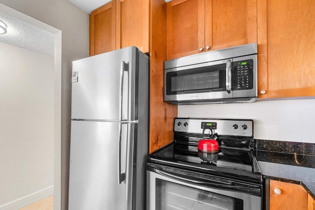 1830 Embassy Dr Unit 401, West Palm Beach, FL 33401 - kitchen featuring appliances with stainless steel finishes, brown cabinetry, and dark stone countertops