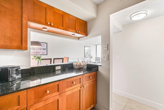 1830 Embassy Dr Unit 401, West Palm Beach, FL 33401 - kitchen featuring brown cabinets, dark stone countertops, and light tile patterned floors