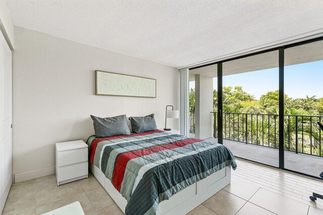1830 Embassy Dr Unit 401, West Palm Beach, FL 33401 - bedroom with a wall of windows, access to exterior, light tile patterned flooring, and a textured ceiling