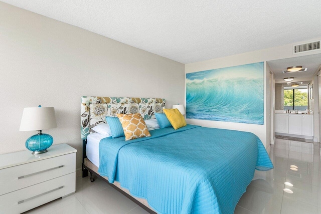1830 Embassy Dr Unit 401, West Palm Beach, FL 33401 - bedroom featuring light tile patterned floors, a textured ceiling, and connected bathroom