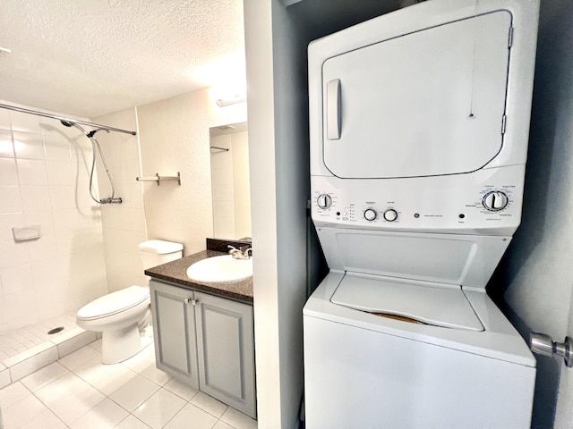 120 Sparrow Dr Unit 302, Royal Palm Beach, FL 33411 - laundry room featuring estacked washer and dryer, a textured ceiling, and light tile patterned floors