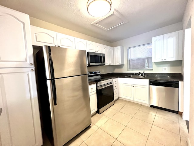 120 Sparrow Dr Unit 302, Royal Palm Beach, FL 33411 - kitchen with stainless steel appliances, dark countertops, white cabinetry, light tile patterned floors, and a textured ceiling