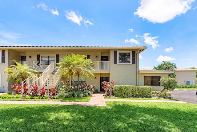 23 Stratford Dr Unit H, Boynton Beach, FL 33436 - view of front of house featuring stucco siding, a front yard, and stairs
