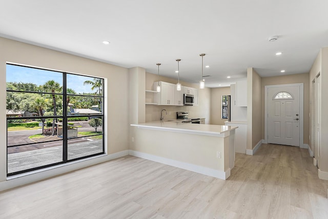 23 Stratford Dr Unit H, Boynton Beach, FL 33436 - kitchen featuring appliances with stainless steel finishes, open shelves, a peninsula, white cabinetry, and light wood-style flooring