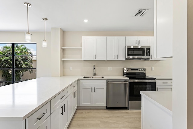 23 Stratford Dr Unit H, Boynton Beach, FL 33436 - kitchen featuring appliances with stainless steel finishes, open shelves, a peninsula, light countertops, and light wood finished floors