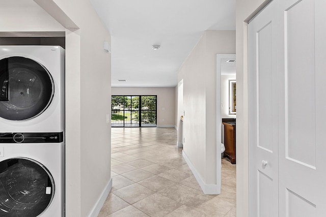 24 Stratford Dr Unit F, Boynton Beach, FL 33436 - washroom featuring stacked washing machine and dryer and light tile patterned flooring