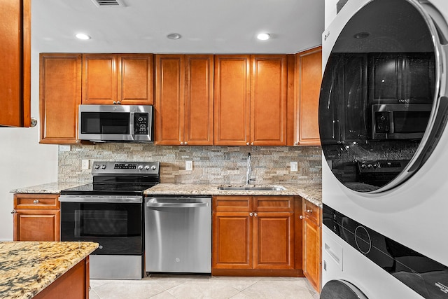 24 Stratford Dr Unit F, Boynton Beach, FL 33436 - kitchen featuring appliances with stainless steel finishes, estacked washer and dryer, brown cabinetry, light stone counters, and recessed lighting
