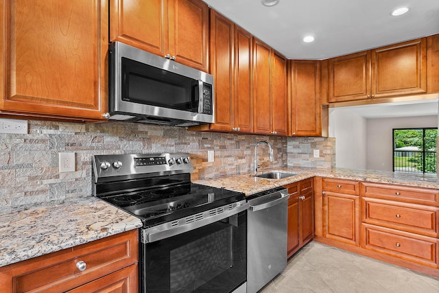 24 Stratford Dr Unit F, Boynton Beach, FL 33436 - kitchen featuring appliances with stainless steel finishes, light stone countertops, brown cabinetry, and recessed lighting