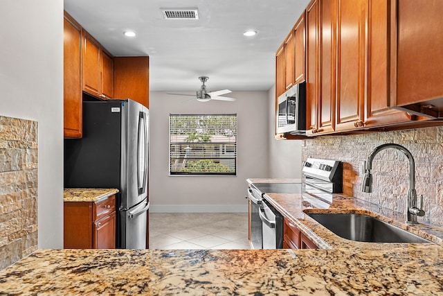 24 Stratford Dr Unit F, Boynton Beach, FL 33436 - kitchen featuring appliances with stainless steel finishes, a ceiling fan, tasteful backsplash, brown cabinets, and light tile patterned floors