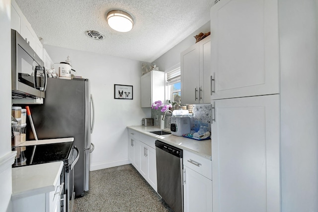 1446 W Perry St, Lantana, FL 33462 - kitchen featuring stainless steel appliances, a textured ceiling, light countertops, white cabinetry, and dark speckled floor