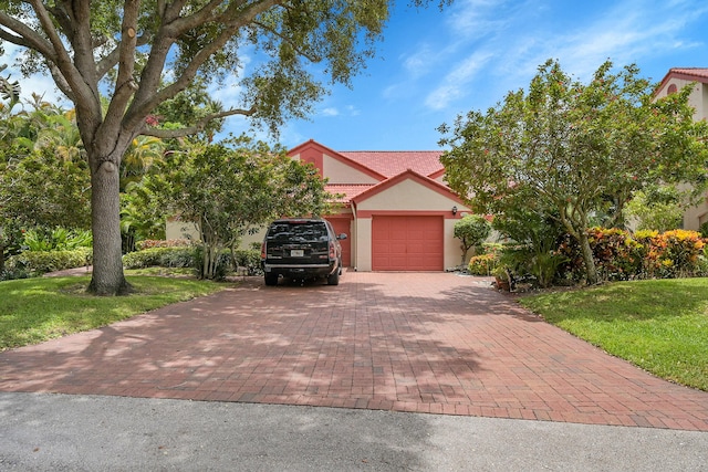 7861 Lexington Club Blvd Unit A, Delray Beach, FL 33446 - view of property hidden behind natural elements with decorative driveway, an attached garage, a tiled roof, and stucco siding