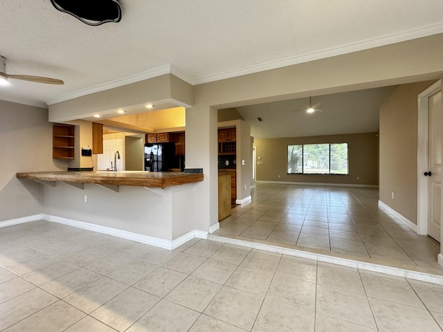 610 SE Forgal St, Port Saint Lucie, FL 34983 - kitchen featuring black refrigerator, light tile patterned floors, crown molding, brown cabinets, and a ceiling fan