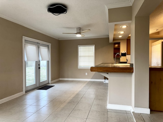 610 SE Forgal St, Port Saint Lucie, FL 34983 - kitchen featuring crown molding, a textured ceiling, light tile patterned flooring, a ceiling fan, and a peninsula