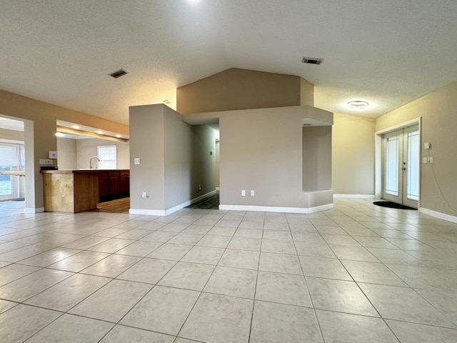 610 SE Forgal St, Port Saint Lucie, FL 34983 - unfurnished room featuring vaulted ceiling, light tile patterned floors, and a textured ceiling