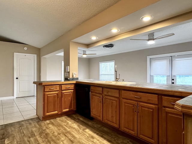 610 SE Forgal St, Port Saint Lucie, FL 34983 - kitchen with dishwasher, ceiling fan, brown cabinetry, light wood finished floors, and a textured ceiling