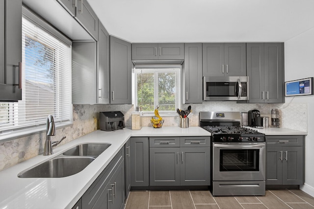 306 N A St, Lake Worth Beach, FL 33460 - kitchen with stainless steel appliances, gray cabinets, backsplash, light countertops, and wood tiled floors