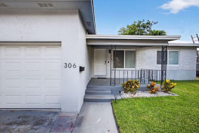 306 N A St, Lake Worth Beach, FL 33460 - entrance to property with covered porch, a lawn, a garage, and stucco siding