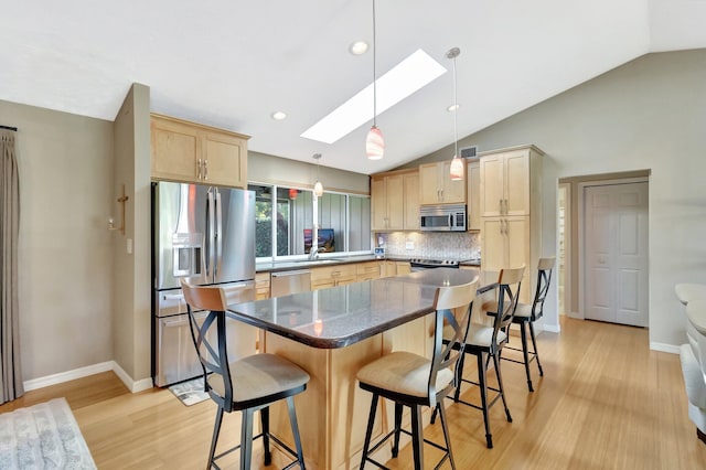 1434 SE Kirke Ln, Port Saint Lucie, FL 34983 - kitchen with stainless steel appliances, light brown cabinetry, a skylight, lofted ceiling, and light wood-style floors