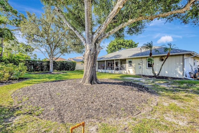 1434 SE Kirke Ln, Port Saint Lucie, FL 34983 - rear view of property with a sunroom, board and batten siding, and a yard