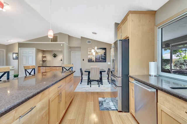 1434 SE Kirke Ln, Port Saint Lucie, FL 34983 - kitchen featuring stainless steel appliances, light brown cabinetry, light wood finished floors, dark stone counters, and lofted ceiling