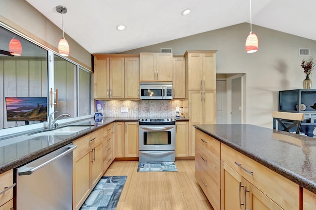 1434 SE Kirke Ln, Port Saint Lucie, FL 34983 - kitchen with appliances with stainless steel finishes, light brown cabinetry, vaulted ceiling, light wood-type flooring, and dark stone countertops