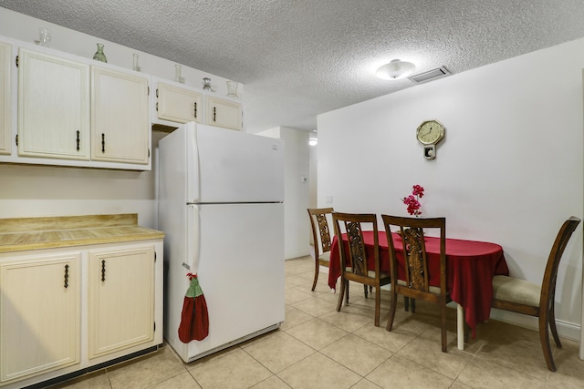968 Sumter Rd W, West Palm Beach, FL 33415 - kitchen with freestanding refrigerator, a textured ceiling, light tile patterned floors, and light countertops