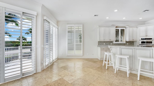 4917 Watersong Way, Fort Pierce, FL 34949 - kitchen with plenty of natural light, crown molding, light countertops, decorative backsplash, and white cabinetry