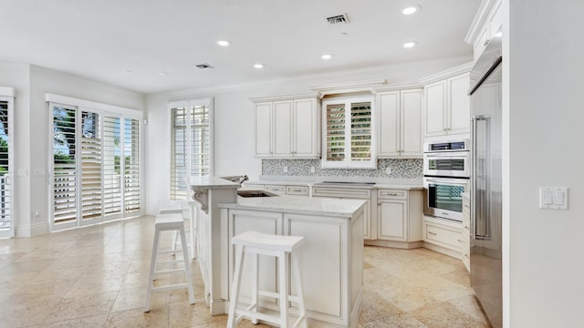 4917 Watersong Way, Fort Pierce, FL 34949 - kitchen featuring double oven, a kitchen breakfast bar, recessed lighting, tasteful backsplash, and light stone countertops