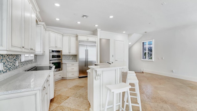 4917 Watersong Way, Fort Pierce, FL 34949 - kitchen featuring stainless steel appliances, decorative backsplash, recessed lighting, a kitchen island with sink, and a breakfast bar