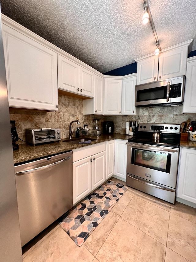 1535 Masters Cir Unit 148, Delray Beach, FL 33445 - kitchen with stainless steel appliances, dark countertops, tasteful backsplash, white cabinets, and light tile patterned floors