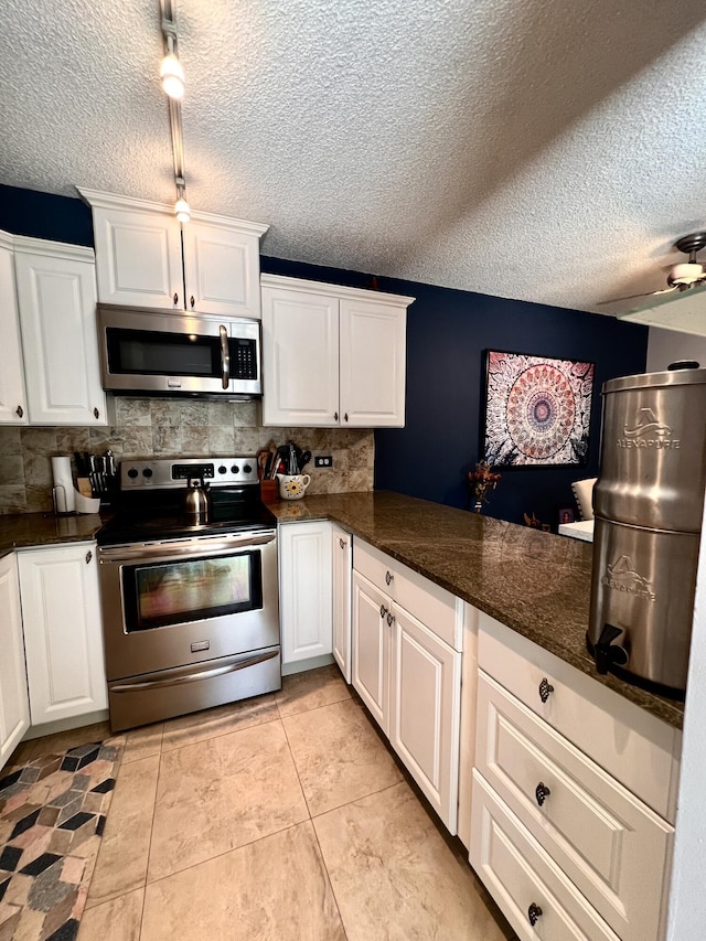 1535 Masters Cir Unit 148, Delray Beach, FL 33445 - kitchen with appliances with stainless steel finishes, decorative backsplash, white cabinets, a textured ceiling, and light tile patterned floors