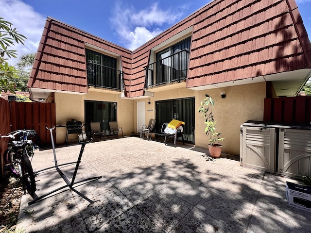 1535 Masters Cir Unit 148, Delray Beach, FL 33445 - back of property with stucco siding, a balcony, a patio area, and mansard roof