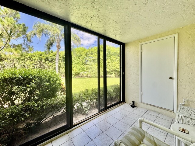 312 Knotty Pine Cir Unit C-1, Greenacres, FL 33463 - unfurnished sunroom with a textured wall, a textured ceiling, tile patterned flooring, and floor to ceiling windows