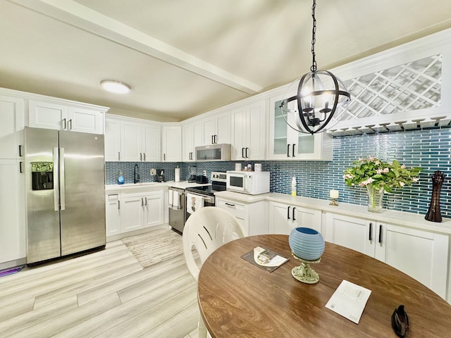 312 Knotty Pine Cir Unit C-1, Greenacres, FL 33463 - kitchen featuring stainless steel appliances, tasteful backsplash, a chandelier, glass insert cabinets, and white cabinetry