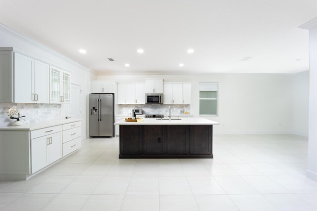 2571 SW Berry Park Cir, Palm City, FL 34990 - kitchen featuring appliances with stainless steel finishes, tasteful backsplash, light countertops, crown molding, and a kitchen island with sink