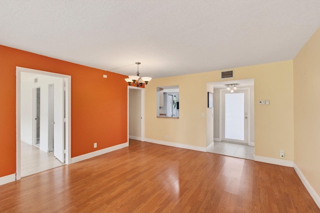 16 Willowbrook Ln Unit 102, Delray Beach, FL 33446 - spare room with a chandelier, light wood finished floors, and a textured ceiling