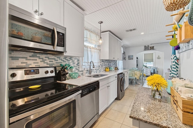 406 N D St, Lake Worth Beach, FL 33460 - kitchen with stainless steel appliances, washer / dryer, light tile patterned floors, tasteful backsplash, and pendant lighting
