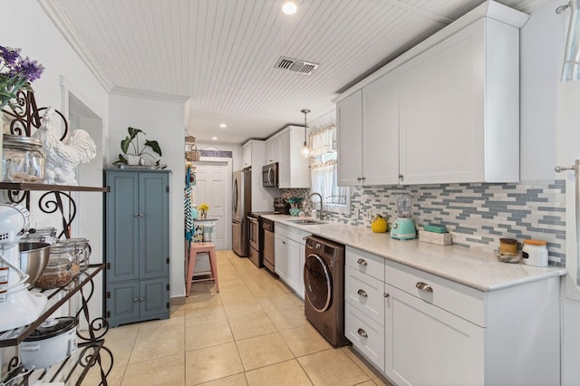 406 N D St, Lake Worth Beach, FL 33460 - kitchen featuring washer / dryer, stainless steel appliances, backsplash, white cabinetry, and light tile patterned flooring