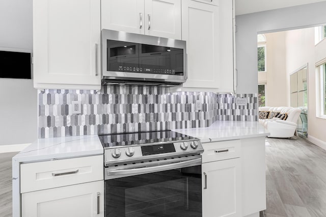 5783 NW 48th Ct, Coral Springs, FL 33067 - kitchen with stainless steel appliances, white cabinets, backsplash, and light stone countertops