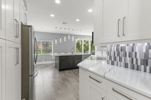 5783 NW 48th Ct, Coral Springs, FL 33067 - kitchen with stainless steel appliances, white cabinetry, recessed lighting, light stone counters, and decorative light fixtures