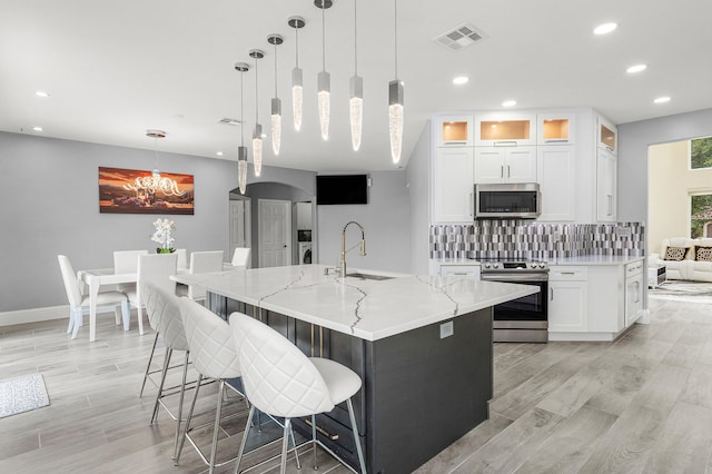 5783 NW 48th Ct, Coral Springs, FL 33067 - kitchen with stainless steel appliances, recessed lighting, white cabinets, backsplash, and light wood finished floors