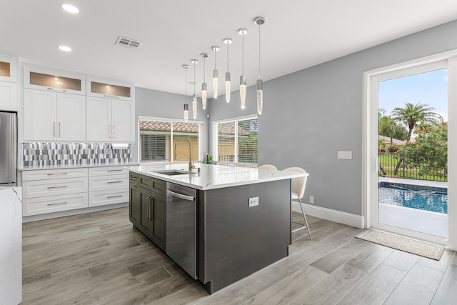 5783 NW 48th Ct, Coral Springs, FL 33067 - kitchen featuring stainless steel appliances, white cabinets, light wood-type flooring, glass insert cabinets, and an island with sink