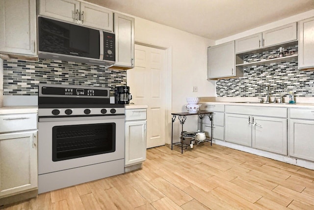 1206 Crestwood Blvd, Lake Worth, FL 33460 - kitchen with range, backsplash, light countertops, and light wood-style flooring