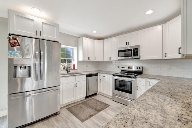 557 SW Violet Ave, Port Saint Lucie, FL 34983 - kitchen featuring appliances with stainless steel finishes, light wood-type flooring, light stone counters, white cabinetry, and recessed lighting
