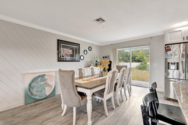 557 SW Violet Ave, Port Saint Lucie, FL 34983 - dining space with light wood-style floors, ornamental molding, and wood walls