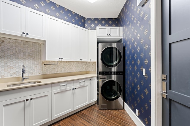 1257 Breakers W Blvd, West Palm Beach, FL 33411 - laundry area featuring stacked washing machine and dryer, cabinet space, wallpapered walls, dark wood finished floors, and a textured ceiling