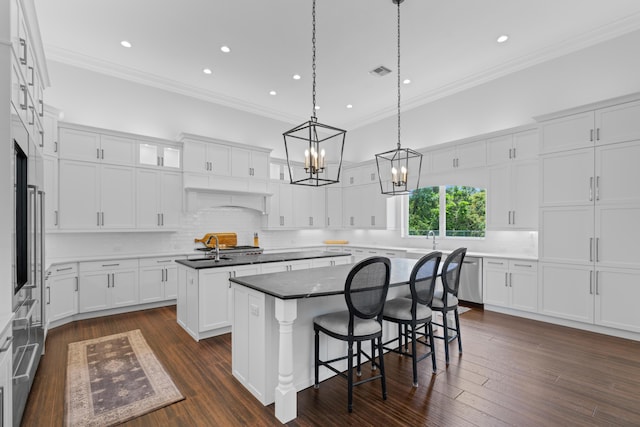 1257 Breakers W Blvd, West Palm Beach, FL 33411 - kitchen featuring a kitchen island, crown molding, decorative backsplash, a breakfast bar area, and white cabinetry