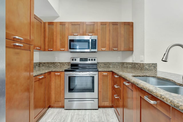 40 SE Sedona Cir Unit 104, Stuart, FL 34994 - kitchen with stainless steel appliances, light stone countertops, brown cabinetry, and light wood-style flooring